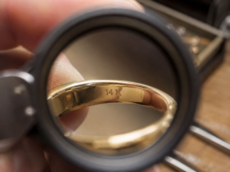 reading14kgoldstampwithjewelersloupe PCL Group Jeweler's loupe magnifying a 14K stamp inside a gold ring band.